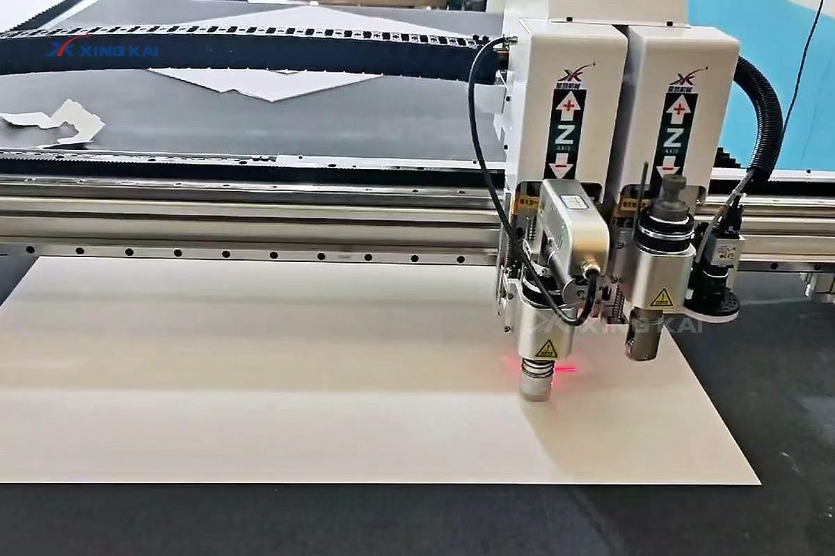 CNC oscillating knife cutting white cardboard sheet for packaging